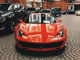 uma ferrari vermelha ao lado de outros carros pretos